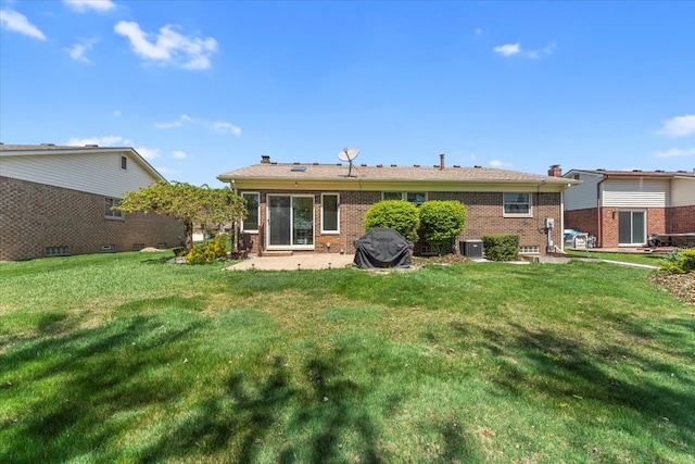 back of property with brick siding, a patio area, central AC, and a yard