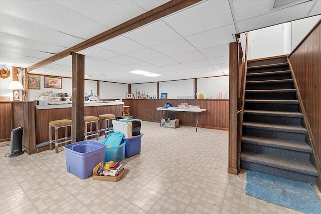 finished basement with wood walls, light floors, and stairway