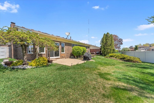 rear view of house featuring fence, a lawn, a patio area, and brick siding