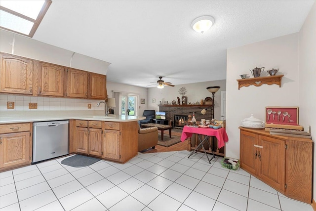 kitchen with a peninsula, open floor plan, ceiling fan, light countertops, and dishwasher