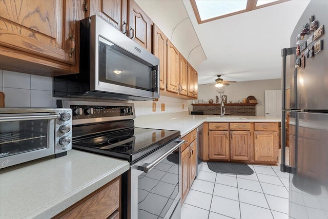 kitchen with decorative backsplash, a sink, light countertops, light tile patterned floors, and stainless steel appliances