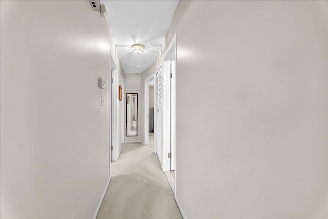 corridor featuring baseboards and light colored carpet