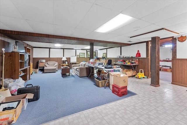 finished below grade area featuring wooden walls, tile patterned floors, wainscoting, and a drop ceiling