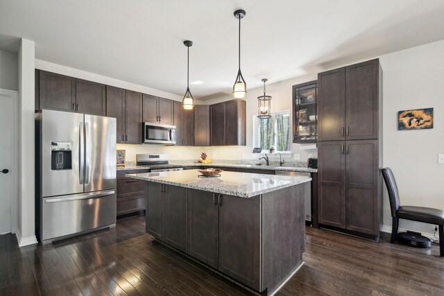 kitchen featuring dark wood finished floors, appliances with stainless steel finishes, dark brown cabinetry, and a kitchen island