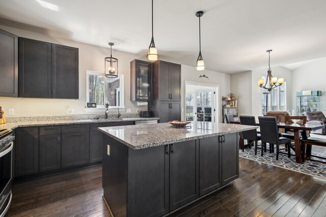 kitchen featuring glass insert cabinets, dark wood-style flooring, a sink, light stone counters, and an inviting chandelier