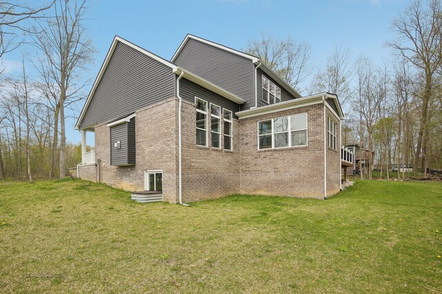 view of home's exterior with brick siding, a yard, and a deck