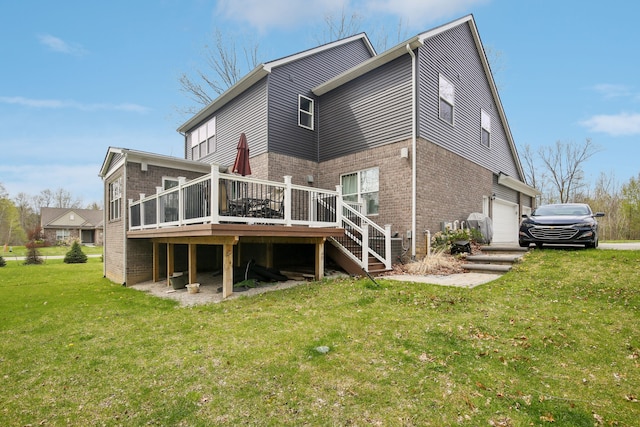 back of house with brick siding, a garage, stairway, a deck, and a yard