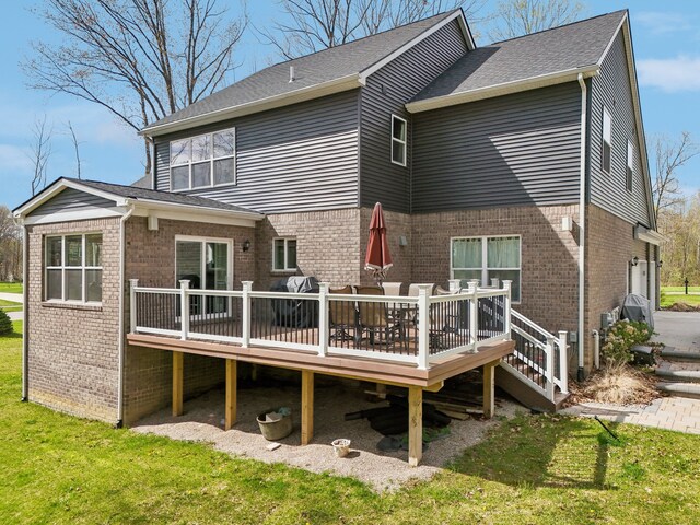 rear view of house featuring a lawn, brick siding, and a deck