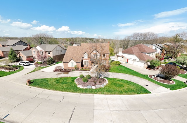 view of front of property featuring curved driveway, a residential view, a front yard, and a garage