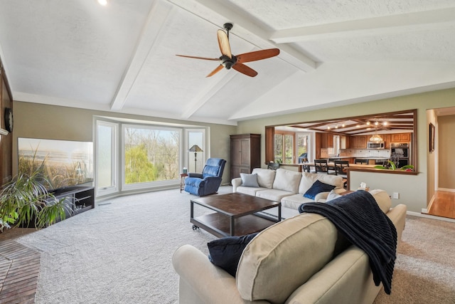 living room with baseboards, lofted ceiling with beams, a ceiling fan, and light carpet