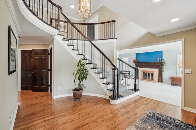 stairway featuring crown molding, wood finished floors, baseboards, recessed lighting, and a chandelier