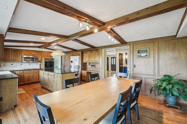 dining room featuring dark wood-style flooring, beam ceiling, and a notable chandelier