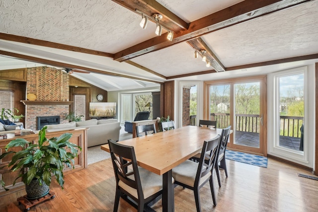 dining room with light wood-style floors, a healthy amount of sunlight, lofted ceiling with beams, and visible vents
