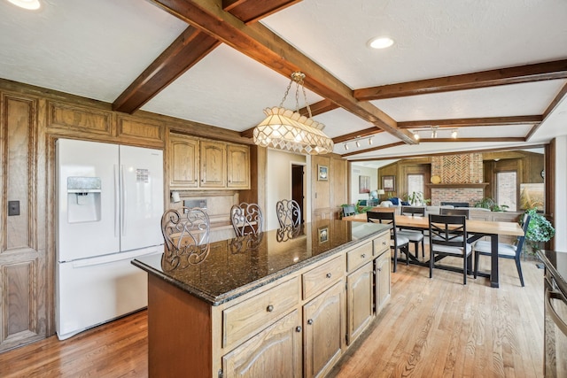 kitchen with a kitchen island, light wood-type flooring, open floor plan, dark stone counters, and white fridge with ice dispenser