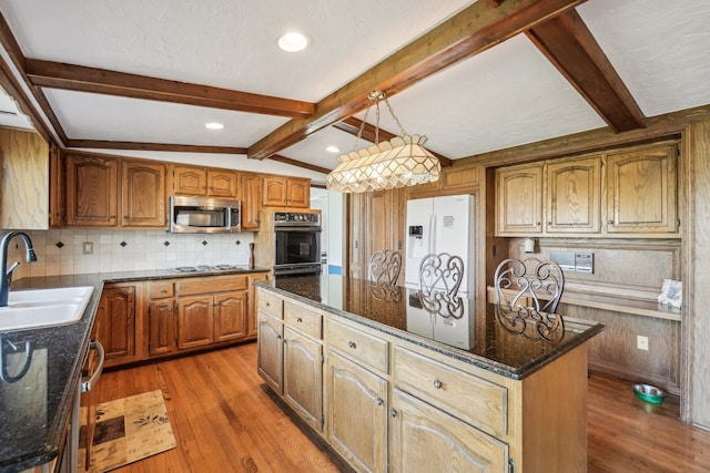 kitchen with a center island, a sink, stainless steel microwave, white fridge with ice dispenser, and oven