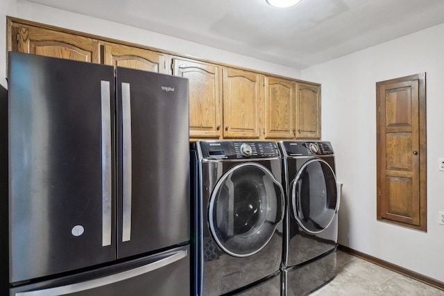 washroom featuring washer and dryer, baseboards, and cabinet space