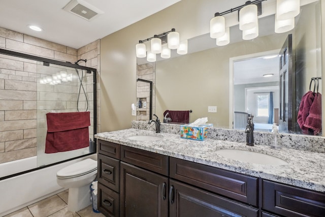 full bathroom with visible vents, a sink, toilet, and bath / shower combo with glass door