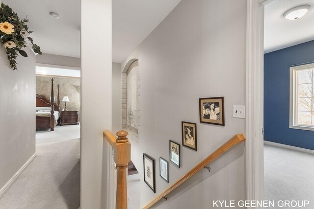 hall featuring baseboards, carpet flooring, and an upstairs landing
