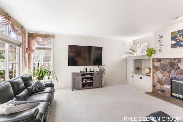 living room with crown molding, a stone fireplace, carpet floors, and a healthy amount of sunlight