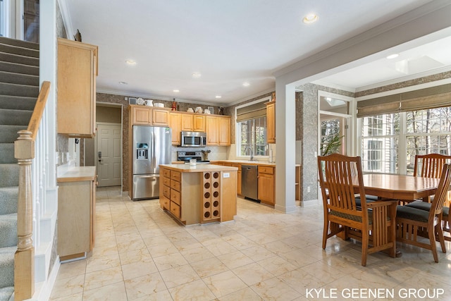 kitchen with ornamental molding, appliances with stainless steel finishes, a kitchen island, and light countertops
