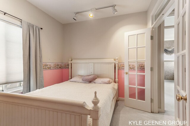 bedroom featuring track lighting and light carpet