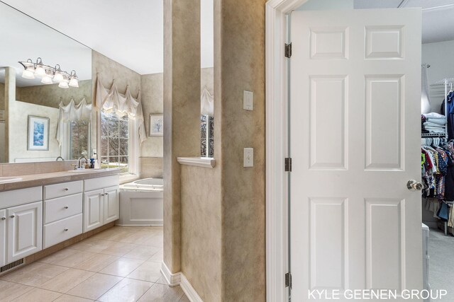 full bathroom with a walk in closet, a sink, double vanity, visible vents, and a garden tub