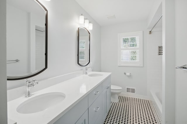 bathroom with visible vents, a sink, double vanity, and toilet