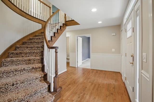 entrance foyer with light wood-type flooring, recessed lighting, stairs, and a wainscoted wall