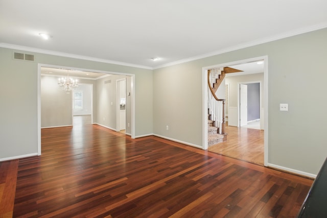 empty room with visible vents, ornamental molding, stairs, wood finished floors, and a chandelier
