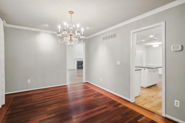 unfurnished dining area featuring crown molding, an inviting chandelier, baseboards, wood finished floors, and visible vents