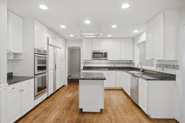kitchen featuring a kitchen island, white cabinetry, appliances with stainless steel finishes, and a sink