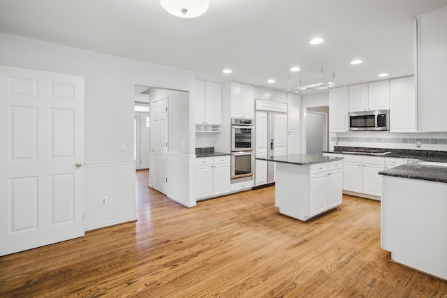 kitchen with light wood-style floors, stainless steel appliances, recessed lighting, white cabinetry, and a kitchen island
