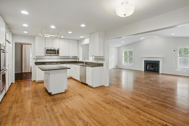 kitchen featuring open floor plan, a center island, white cabinetry, a sink, and appliances with stainless steel finishes
