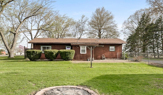 rear view of house featuring fence and a yard