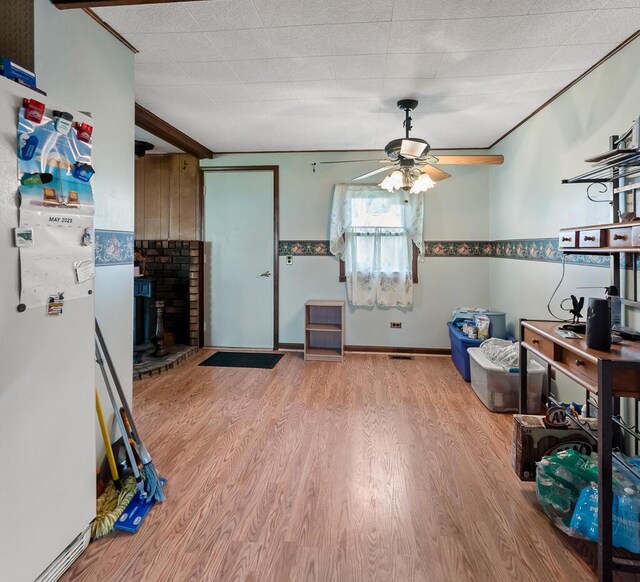 interior space featuring a brick fireplace, ceiling fan, and wood finished floors