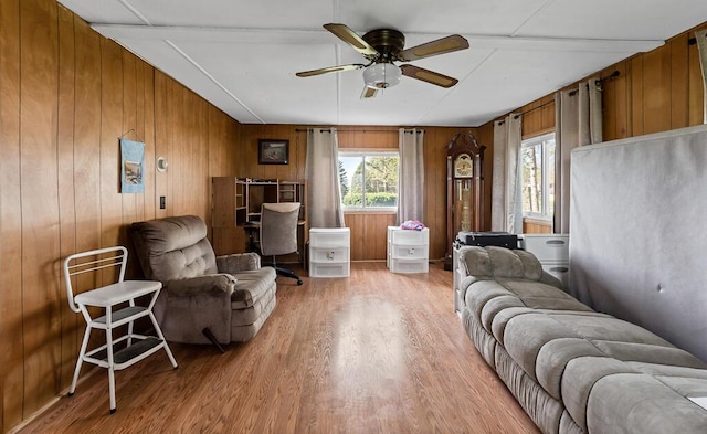 living room featuring a ceiling fan, wood finished floors, and wooden walls