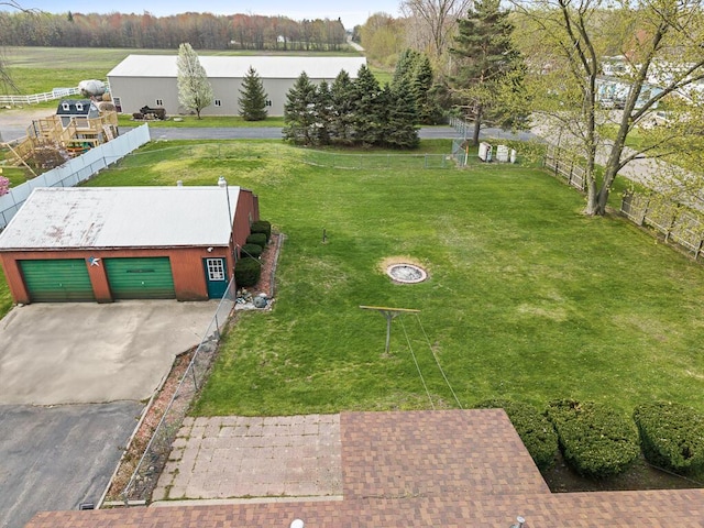 view of yard with aphalt driveway, fence, an outbuilding, and a garage