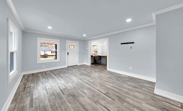 unfurnished living room with crown molding, wood finished floors, and baseboards