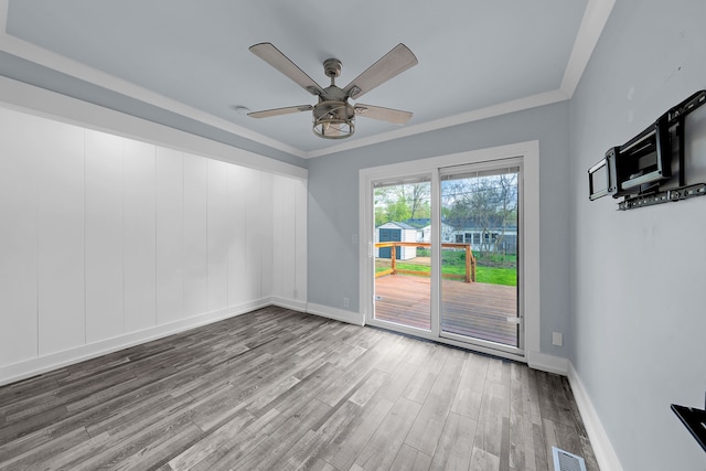 empty room featuring baseboards, ceiling fan, visible vents, crown molding, and wood finished floors