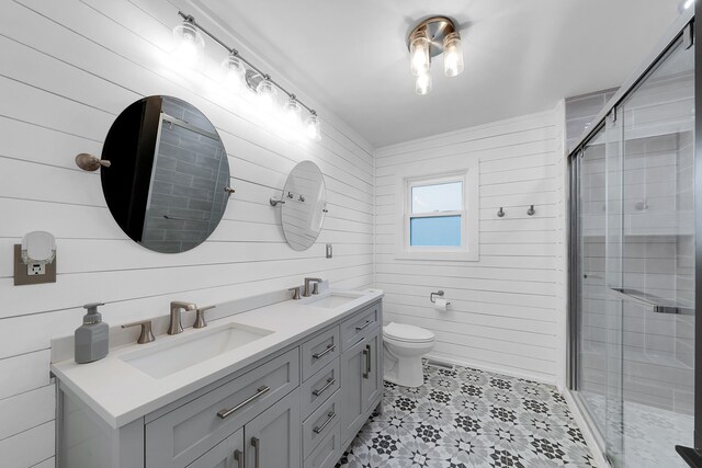 bathroom featuring toilet, double vanity, a sink, and a shower stall