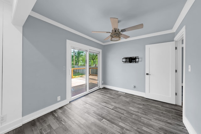 empty room with crown molding, wood finished floors, baseboards, and ceiling fan