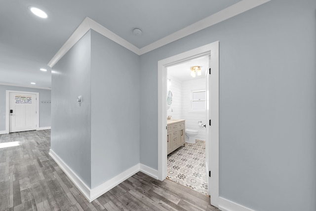 hallway with crown molding, recessed lighting, baseboards, and wood finished floors