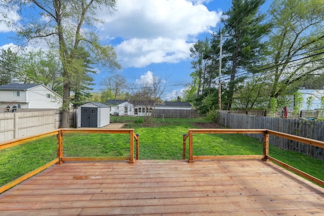 deck featuring a fenced backyard, an outdoor structure, a shed, and a lawn