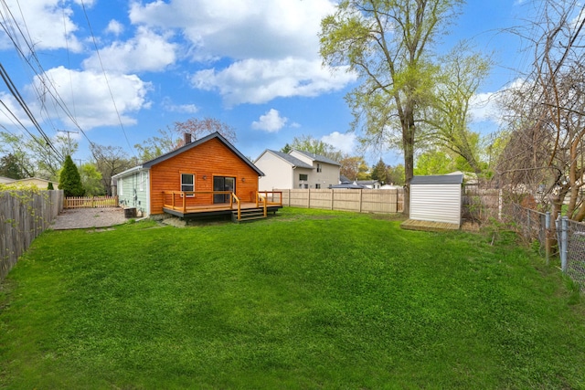 back of house featuring a fenced backyard, a deck, a storage shed, and a yard
