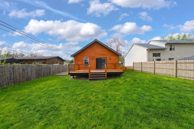 rear view of property featuring a yard, a deck, and a fenced backyard