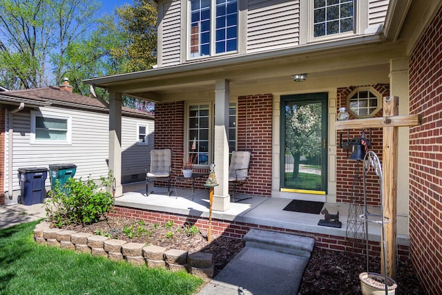 doorway to property featuring a porch and brick siding