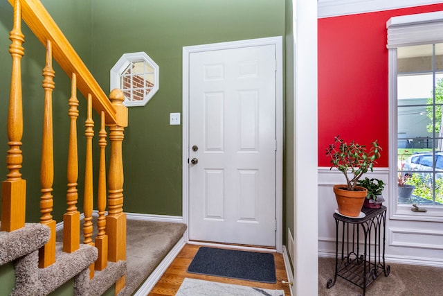 entryway with stairway, a wainscoted wall, wood finished floors, and a wealth of natural light