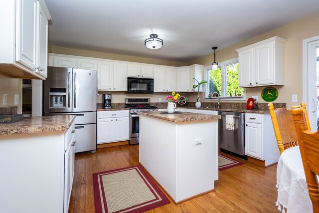 kitchen with light wood-style floors, a center island, white cabinetry, a sink, and stainless steel appliances