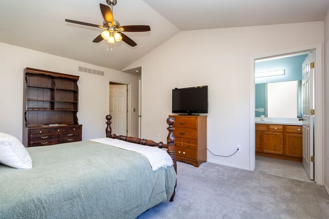 bedroom featuring visible vents, light colored carpet, connected bathroom, a sink, and vaulted ceiling