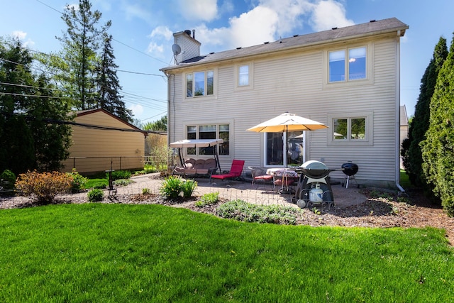 back of house featuring a lawn, a patio area, fence, and a chimney